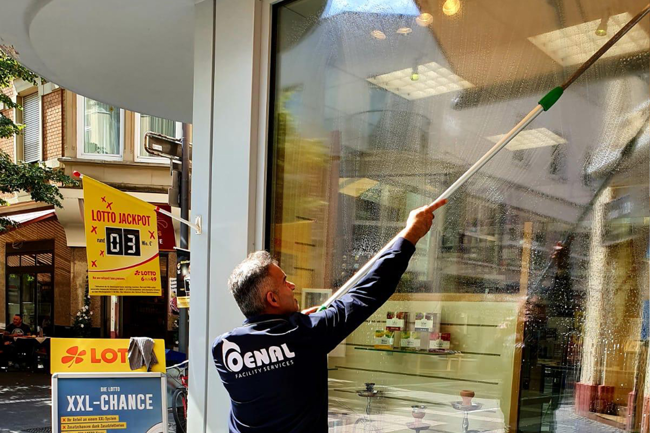 Mitarbeiter von der Oenal Gebäudereinigung in Obertshausen reinigt die Fenster von einem Kiosk