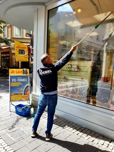 Glas und Fensterreinigung Oenal Mitarbeiter von der Oenal Gebäudereinigung in Obertshausen reinigt die Fenster von einem Kiosk